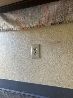 An electrical outlet installed upside down in a wall.
